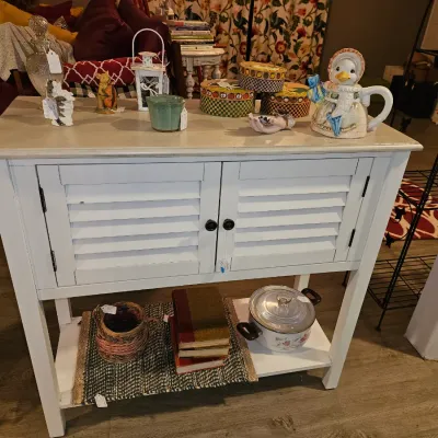 Sale Photo Thumbnail #56: White-painted shutter-door sideboard console table displaying home decor items including a duck teapot, stacked hat boxes, and small figurines.