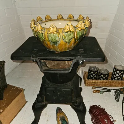Sale Photo Thumbnail #54: Whimsical ceramic frog-rimmed bowl resting on a vintage cast-iron salesman sample or laundry stove, displayed alongside small decor items inside a brick fireplace hearth.