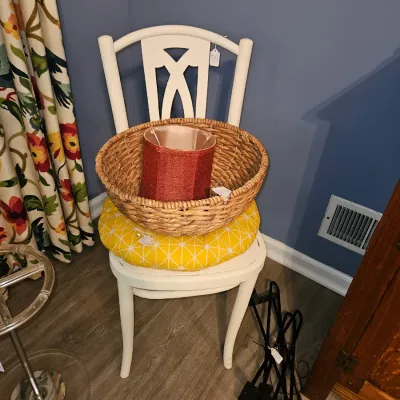 Sale Photo Thumbnail #38: Off-white wooden side chair featuring a yellow geometric cushion, paired with a woven wicker basket and a red lampshade.