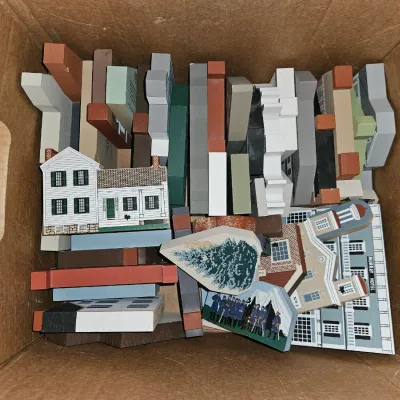 Sale Photo Thumbnail #50: Cardboard box filled with vintage printed wooden architectural blocks, including house facades, trees, and historical buildings from series like The Cat's Meow Village.