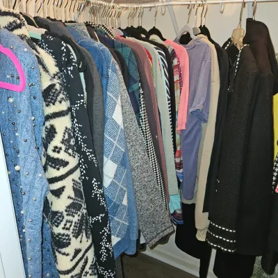Sale Photo Thumbnail #72: A walk-in closet filled with assorted women's sweaters, jackets, and long-sleeve tops on wire shelving hangers.
