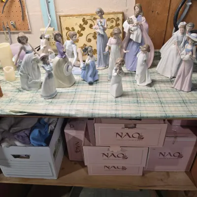 Sale Photo Thumbnail #216: Collection of Nao by Lladró porcelain figurines featuring various human figures and bridal subjects, displayed with original branded boxes below.