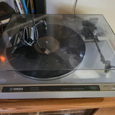 Sale Photo Thumbnail #182: Vintage Yamaha P-300 semi-automatic direct drive turntable, featuring a tinted dust cover and classic silver faceplate design.