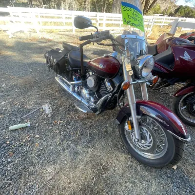 Sale Photo Thumbnail #127: 2001 Yamaha V-Star 650 Classic cruiser motorcycle in maroon, equipped with a windshield, chrome exhaust, and black leather saddlebags.