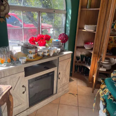 Sale Photo Thumbnail #54: Rustic modern entertainment center with built-in electric fireplace insert, displayed alongside a collection of sunflower-themed mugs and glassware.