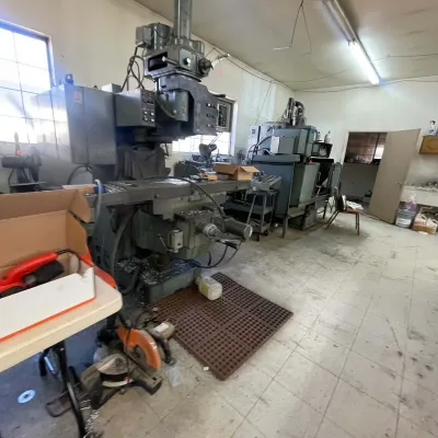 Sale Photo Thumbnail #100: Industrial metalworking milling machine and shop equipment set up inside a workshop.