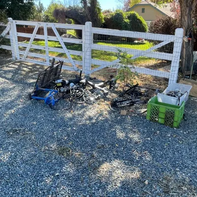 Sale Photo Thumbnail #35: Assorted towing accessories, trailer equipment, and cargo carriers laid out on a gravel driveway near a fence.