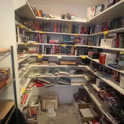 Sale Photo Thumbnail #81: Walk-in closet lined with built-in white shelving filled with books, media, binders, and organizational supplies.