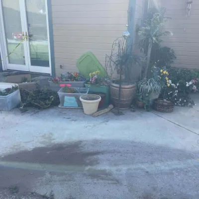 Sale Photo Thumbnail #85: Assortment of outdoor decor including potted faux and real plants, plastic storage bins with faux flowers, and ceramic planters on a patio.