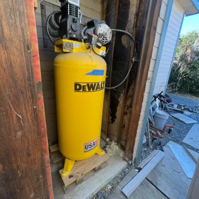 Sale Photo Thumbnail #109: Large yellow DeWalt vertical air compressor, mounted on a wooden base with visible pressure gauge and top-mounted motor.