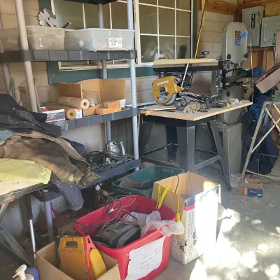 Sale Photo Thumbnail #88: Workshop area featuring a DeWalt Powershop 250 radial arm saw, standing band saw, plastic shelving units, and various storage totes with power tools.