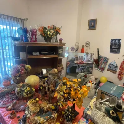 Sale Photo Thumbnail #118: Collection of autumn and holiday decor, including artificial foliage arrangements, scarecrow figurines, wall art, and a large wooden display cabinet.