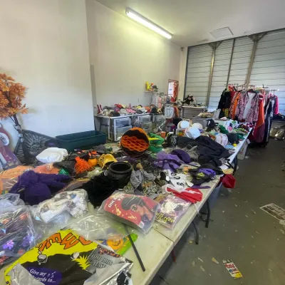 Sale Photo Thumbnail #145: Large collection of Halloween costumes, wigs, decorations, and party accessories arranged on long folding tables.