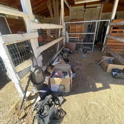 Sale Photo Thumbnail #38: Rustic barn storage area containing an assortment of items including a dusty upright vacuum, boxed goods, tools, and outdoor equipment.