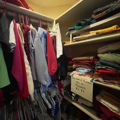 Sale Photo Thumbnail #67: A walk-in closet filled with hanging casual apparel alongside shelves neatly stacked with table linens, placemats, and runners.