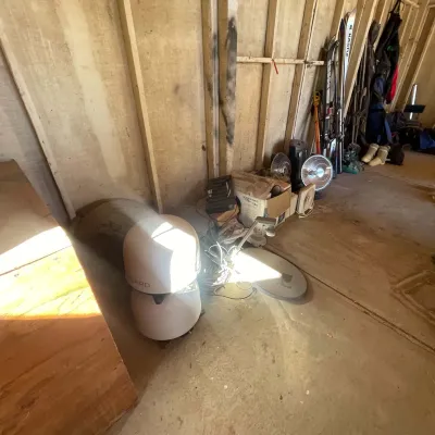 Sale Photo Thumbnail #107: Assorted workshop and storage items including a satellite dish antenna, portable space heaters, box fans, and vintage snow skis.