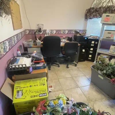 Sale Photo Thumbnail #76: Home office filled with various furniture and supplies, including black rolling desk chairs, filing cabinets, office electronics, and faux floral arrangements.