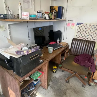 Sale Photo Thumbnail #44: Cluttered home office setup featuring a mid-century wooden desk, a brown faux-leather rolling chair, a computer monitor, software, and various office supplies.