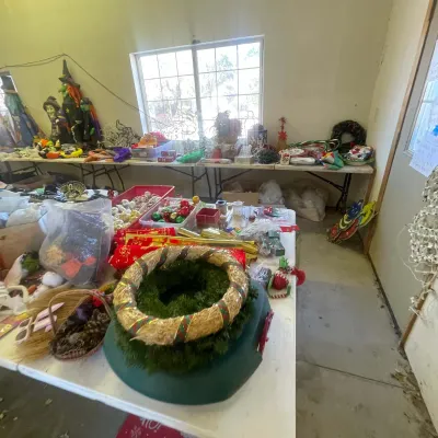 Sale Photo Thumbnail #139: Assortment of holiday decor displayed on tables, featuring Christmas wreaths, ornaments, and Halloween witch figures.