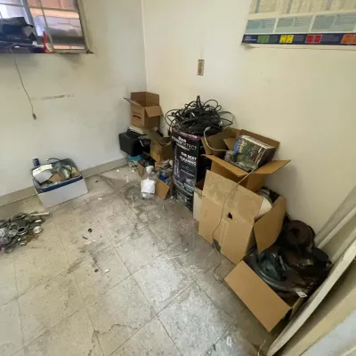 Sale Photo Thumbnail #104: Assorted cardboard boxes filled with electronics, cables, household items, and hardware stored in a room.