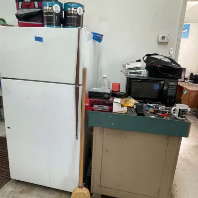 Sale Photo Thumbnail #41: White top-freezer refrigerator positioned next to a green-topped wooden cabinet featuring a countertop microwave, car audio receivers, and paint cans.