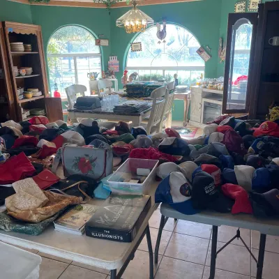 Sale Photo Thumbnail #50: Large collection of vintage baseball caps and trucker hats laid out on folding tables alongside handbags and game boxes.