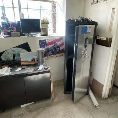 Sale Photo Thumbnail #40: Tall Henry Protector gun safe with a electronic keypad, standing next to a black storage cabinet in an office setting.