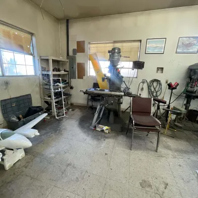 Sale Photo Thumbnail #95: Workshop space featuring a vintage Bridgeport vertical milling machine, model airplane parts, metal shelving, and various shop tools.
