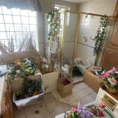 Sale Photo Thumbnail #75: Large collection of faux floral arrangements, artificial greenery, and craft supplies packed into boxes and totes in a tiled bathroom.