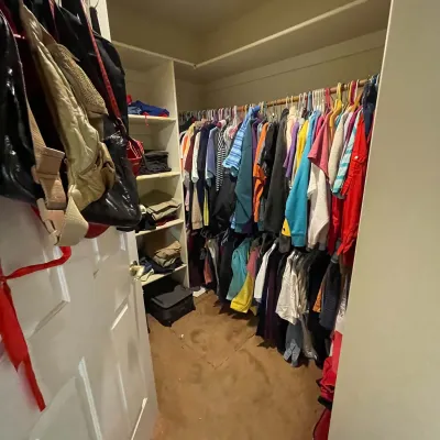 Sale Photo Thumbnail #11: Walk-in closet filled with assorted men's and women's clothing, hanging bags, and folded garments on shelving.