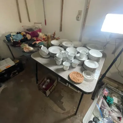 Sale Photo Thumbnail #34: Large collection of white porcelain chinaware set on a folding table, alongside plush dolls and miscellaneous household items.