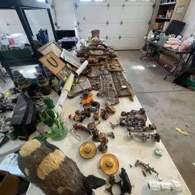 Sale Photo Thumbnail #16: Large garage sale collection of Western-themed decor items, including small figurines, ceramic sombrero salt and pepper shakers, wooden wall plaques, and framed artwork.