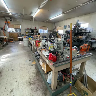 Sale Photo Thumbnail #94: Workshop room filled with heavy machinery, long workbenches, power tools, hand tools, and hardware equipment.