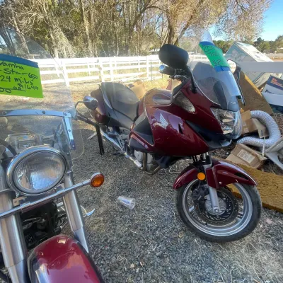 Sale Photo Thumbnail #134: Burgundy Honda NT700V touring motorcycle parked outdoors, featuring a large windshield, front fairings, and integrated saddlebags.