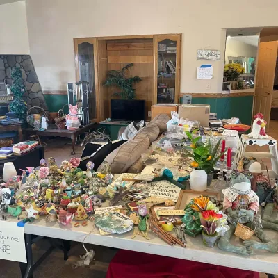 Sale Photo Thumbnail #58: Large collection of novelty knick-knacks, frog figurines, decorative signs, and artificial plants arranged on folding tables.