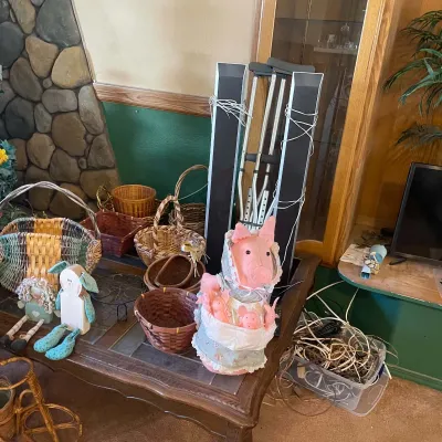 Sale Photo Thumbnail #66: Collection of woven baskets, plush pig doll, wooden decorations, and medical crutches displayed on a tile-top coffee table.