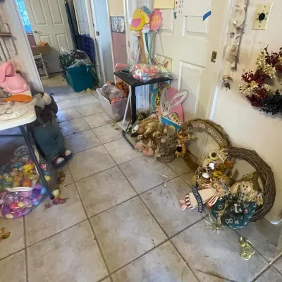 Sale Photo Thumbnail #78: Collection of seasonal holiday decor, including autumn and Easter wreaths, plastic eggs, cutout signs, and plush figures set up along a hallway.