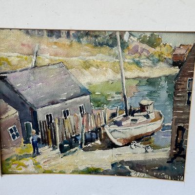 Sale Photo Thumbnail #175: Matted original watercolor painting depicting a coastal harbor scene with a sailboat docked beside seaside shacks.
