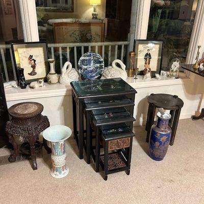 Sale Photo Thumbnail #83: Collection of Asian decor and furniture including a black lacquer nesting table set with mother-of-pearl inlay, carved marble-top plant stand, ceramic swans, porcelain vases, and framed artwork.