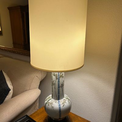 Sale Photo Thumbnail #30: Vintage Asian-style ceramic table lamp featuring a bamboo leaf motif on a dark wood base, topped with a tall cylindrical shade.