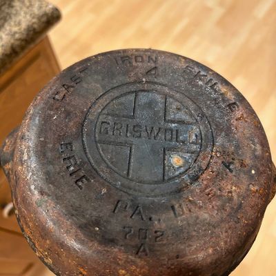 Sale Photo Thumbnail #31: Vintage Griswold No. 4 cast iron skillet, featuring the large block logo with cross markings on the bottom, displaying surface rust and wear consistent with age.