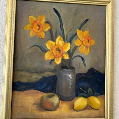 Sale Photo Thumbnail #172: Framed still life oil painting depicting yellow daffodils in a grey vase with fruit on a table, housed in a molded metallic gold frame.