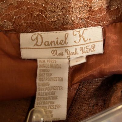 Sale Photo Thumbnail #76: Close-up of a Daniel K. New York USA clothing brand and material care tag inside a rust-colored lace garment.