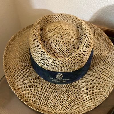 Sale Photo Thumbnail #10: Vintage straw sun hat featuring a wide brim and a navy blue hatband embroidered with The Ritz-Carlton Mauna Lani logo.