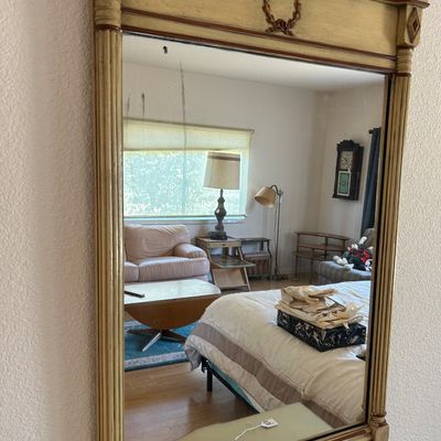 Sale Photo Thumbnail #182: French Neoclassical style trumeau-style wall mirror with an antiqued cream and gilt painted frame featuring fluted side columns and a top wreath motif.