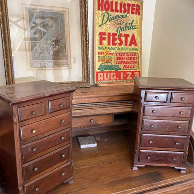 Sale Photo Thumbnail #135: Pair of vintage wooden tabletop mini-chests of drawers alongside an ornate gold-framed print and a vintage Hollister Diamond Jubilee Fiesta cardboard poster.