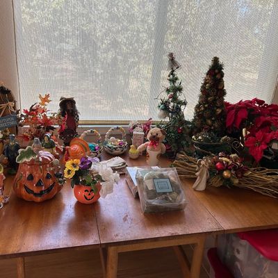 Sale Photo Thumbnail #184: Collection of seasonal holiday decor displayed on a mid-century wooden drop-leaf dining table, including Halloween, Thanksgiving, Easter, and Christmas items.
