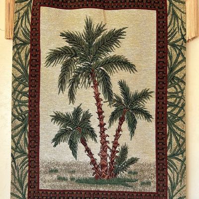 Sale Photo Thumbnail #138: Woven tropical wall tapestry featuring palm trees, suspended from a decorative wooden rod with tassel finials.