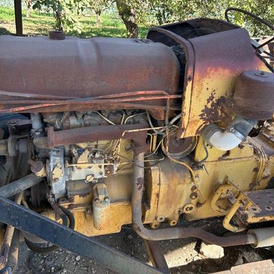 Sale Photo Thumbnail #127: Vintage yellow tractor featuring visible engine components, surface rust, and weathered bodywork.
