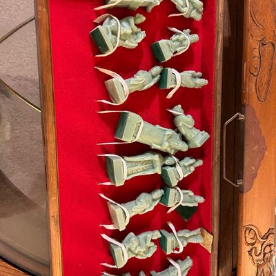Sale Photo Thumbnail #79: Set of carved celadon green stone or resin Asian-style chess pieces, secured inside a red felt-lined fitted wooden display box with carved exterior details.